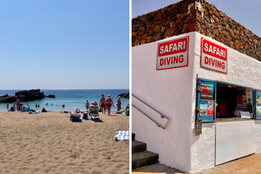 Zandstrand met mensen bij de oceaan links; wit gebouw met "Safari Diving"-borden rechts.